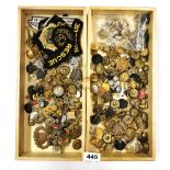 Two trays of military buttons and cap badges.
