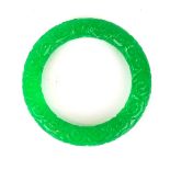 A Chinese carved green jade bangle width 13mm. Dia. 6cm.