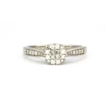 A white metal (tested 9ct gold) diamond cluster ring with diamond set shoulders, (P).
