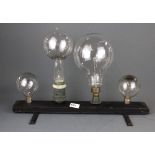 A wooden stand mounted with four early electric light bulbs, H. 34cm