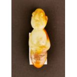 An interesting Chinese carved celadon and russet jade amulet with a human head and arms and an