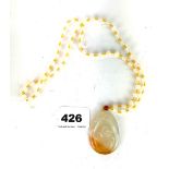 A Chinese polished white and russet agate amulet of the happy Buddha on a white agate bead and