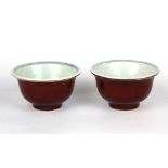 A pair of Chinese porcelain tea bowls with exterior sang de boeuf glaze and interior hand painted
