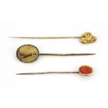 A 9ct yellow gold stick pin, with a further two yellow metal stick pins, one set with coral and