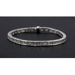 A white metal (tested 18ct gold) baguette cut diamond line bracelet, approx.6ct, L. 18.5cm.