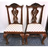 A pair of Georgian carved walnut country dining chairs with shell backs and ball and claw feet.