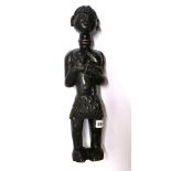 An African carved Punu Tribal fertility figure of a woman feeding a baby, H. 42cm.