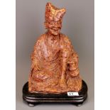 A large early 20th century Chinese carved hardstone figure of a seated Arhat on a carved wooden