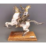 A silvered and gilt heavy metal figure of a Viking riding a horse (figure detachable) set on a brown