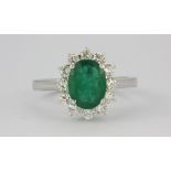 An 18ct white gold (stamped 750) ring set with an oval cut emerald surrounded by diamonds (O.5)