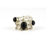 A white metal ring set with black stones.