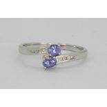 A 9ct white gold tanzanite and diamond set crossover ring, (P.5).