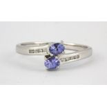 A 9ct white gold tanzanite and diamond set crossover ring, (P.5).