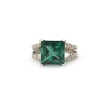 A 9ct white gold (stamped 375) ring set with a green stone and diamond set shoulders, (N.5).
