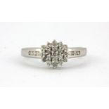 A 9ct white gold diamond set cluster ring with diamond set shoulders, (K).