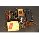 A Rolleicord twin lens reflex camera with a further folding camera, a pair of early binoculars and a