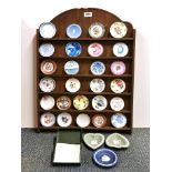 A collectors cabinet with a collection of miniature porcelain plates and certificates.