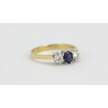 An 18ct yellow and white gold ring set with an oval cut sapphire flanked by brilliant cut