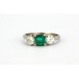 A 925 platinum ring set with a 0.65ct emerald flanked by brilliant cut diamonds (approx. 0.90ct