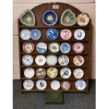 A collectors cabinet with a collection of miniature porcelain plates and certificates.