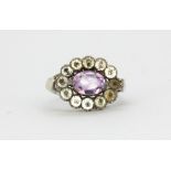 A white metal (tested silver) amethyst and white stone set cluster ring, (L.5).