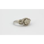 A 9ct white gold diamond set cluster ring with diamond set shoulders, (L).