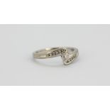 An 18ct white gold ring set with a brilliant cut diamond and diamond set shoulders, (P).