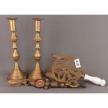 A Victorian brass trivet, a pair of heavy brass candlesticks and an item of leather and brass