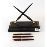 A rollerball pen together with two Waterman rollerball pens and a pen stand. All