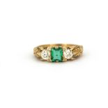 A yellow metal (tested 18ct gold) ring set with an emerald cut natural emerald flanked by