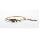 A yellow metal (tested minimum 9ct gold) bangle set with a sapphire and brilliant and rose cut