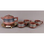 A Chinese Yixing terracotta teapot with four cups and brass teapot stand, H. 9cm, spout to handle