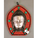 A Tibetan polished cast iron and bead mounted Buddha head wall panel, H. 28cm.