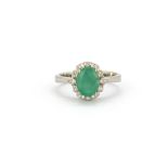 A 925 silver 925 silver cluster ring set with an oval cut emerald surrounded by white stones, (Q).
