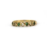 A 9ct yellow gold emerald and white stone set half eternity ring, (M.5).