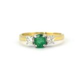 An 18ct yellow and white gold ring set with an oval cut emerald flanked by brilliant cut