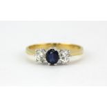 An 18ct yellow and white gold ring set with an oval cut sapphire flanked by brilliant cut