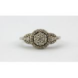 A 9ct white gold diamond set cluster ring with diamond set shoulders, (L).
