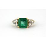 A yellow metal (tested 18ct gold) ring set with a 2.5ct emerald cut emerald and brilliant cut