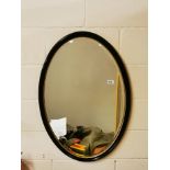 A 1920's oval framed bevelled glass mirror, 59 x 90cm.