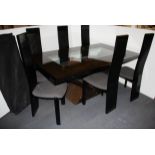 An impressive contemporary black lacquered snakewood dining table and six chairs with a smoked glas