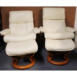 A pair of contemporary Ekornes reclining armchairs with matching foot stools and adjustable head