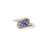 A 9ct white gold tanzanite and diamond set crossover ring, (N.5).