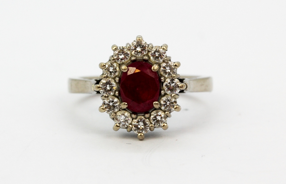 An 18ct white gold cluster ring set with an oval cut ruby surrounded by brilliant cut diamonds, (