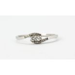 A 9ct white gold diamond set crossover ring, (S).
