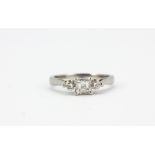 A 950 platinum ring set with a princess cut diamond flanked by brilliant cut diamonds, (I.5).