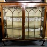 A 1920's ball and claw foot mahogany bowed front cabinet, W. 122cm. H. 134cm.