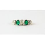 An 18ct yellow and white gold ring set with oval cut emeralds and old cut diamonds, (P).