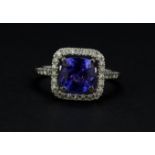 An 18ct white gold cluster ring set with a cushion cut tanzanite surrounded by brilliant cut