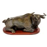 A Chinese bronze coloured terracotta figure of a water buffalo on a wooden pedestal, L. 46cm.